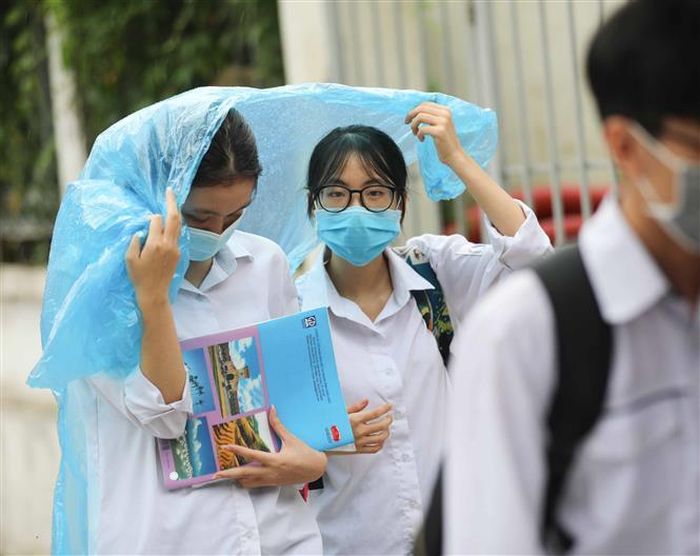 Thí sinh rời điểm thi trường THCS Lê Ngọc Hân (quận Hai Bà Trưng) trong mưa. Ảnh: Thanh Tùng - TTXVN