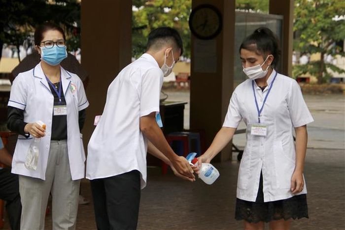 Thí sinh thực hiện rửa tay sát khuẩn và mang khẩu trang y tế trước khi vào phòng thi. Ảnh: Kim Há-TTXVN