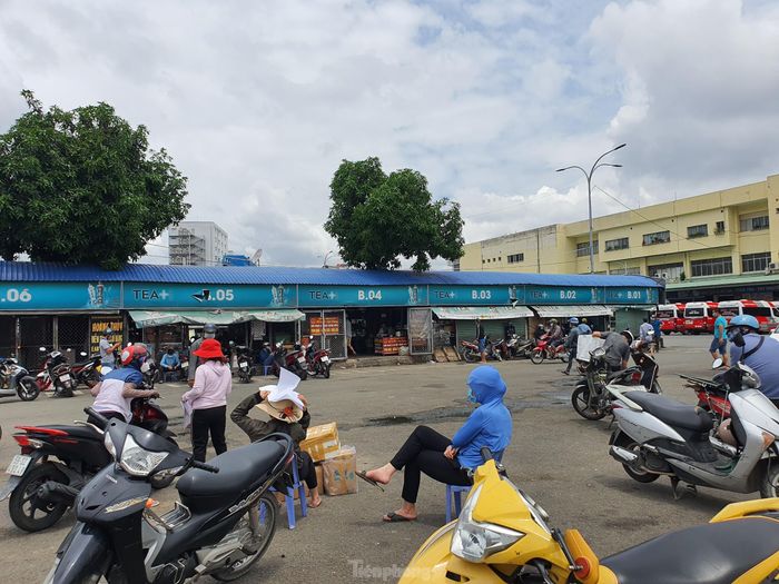 Do khu vực giao hàng hóa không có chỗ ngồi nên người dân phải ngồi giữa sân bê tông dưới thời tiết nóng bức.