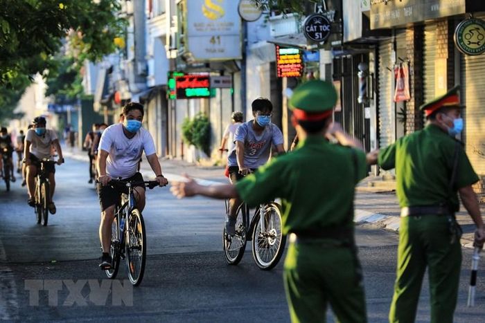  Lực lượng công an phường Thụy Khuê nhắc nhở người dân quay đầu không tụ tập đạp xe tập thể dục tại đường Nguyễn Đình Thi - chụp 6h sáng 16/7. (Ảnh: Thành Đạt/TTXVN) 