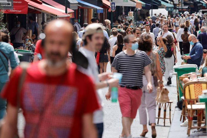 Người dân đi lại trên đường phố Paris vào ngày 17/6, một số người không đeo khẩu trang vì không còn quy định buộc đeo khẩu trang ngoài trời. Ảnh: Reuters.
