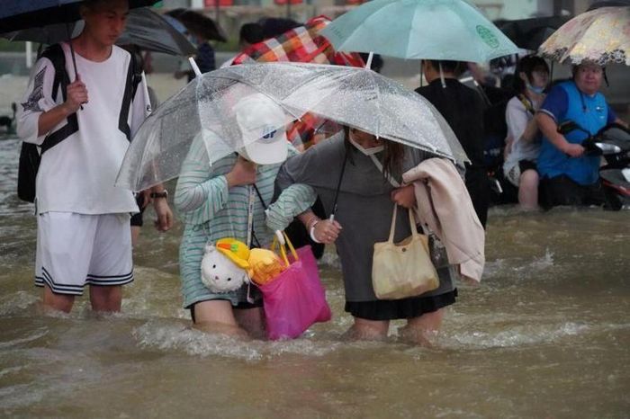 Người dân Trịnh Châu chật vật di chuyển trong mưa lũ hôm 20/7.