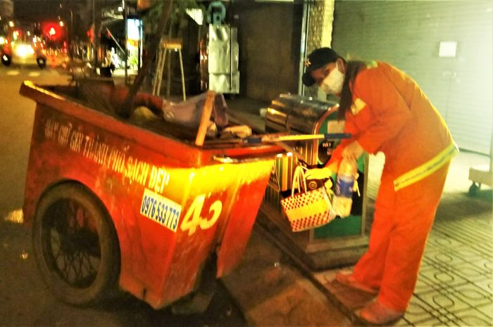 Nhân viên lao công đang thu dọn rác tại khu vực chốt trực chống COVID-19 trên đường Huỳnh Tấn Phát, quận 7.