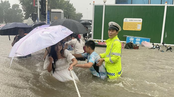  Nhiều người dân mắc kẹt tại các trường học, căn hộ, văn phòng và thậm chí là hệ thống tàu điện ngầm. Trong ảnh, cảnh sát giao thông giúp người dân bám vào dây thừng di chuyển để tránh bị dòng nước cuốn đi. Hôm 21/7, chính quyền Trịnh Châu cho biết 12 người thiệt mạng khi nước tràn vào tàu điện ngầm. Ảnh: Reuters. 