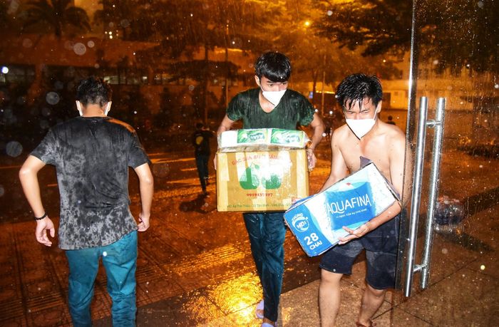  Lực lượng dân quân đội mưa chuyển đồ cho bệnh nhân F0. Ảnh: Ngọc Tân. 
