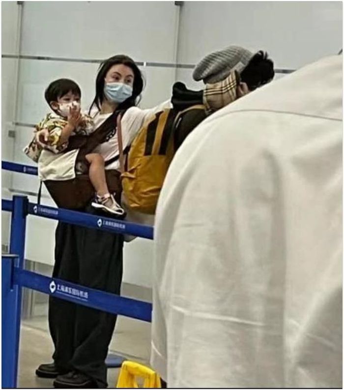 Trương Bá Chi tay xách nách mang và bế con trai út.