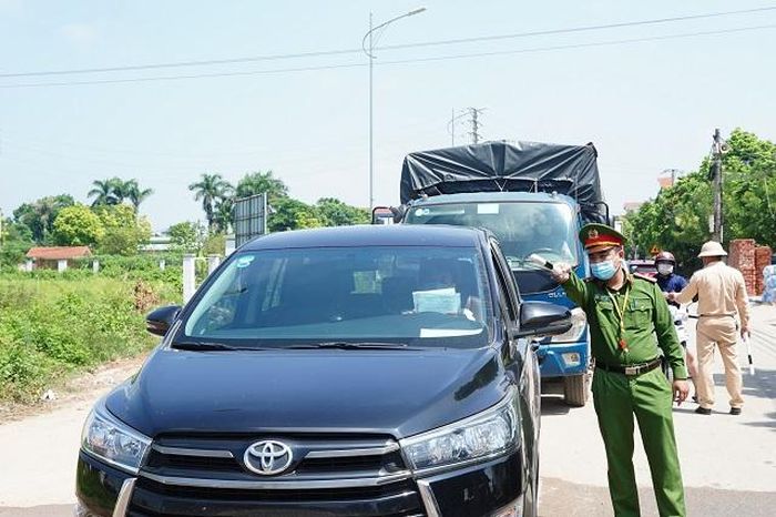 Lực lượng chức năng làm nhiệm vụ tại chốt kiểm soát y tế giữa Hà Nội và Vĩnh Phúc. Ảnh: Phạm Hùng