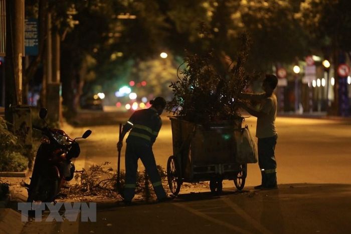 Đêm đêm, trên những con phố vắng lặng vẫn luôn có những người cần mẫn làm sạch phố phường. (Ảnh: Minh Quyết/TTXVN)