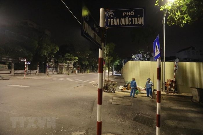 Thu gom rác xong, những người lao công lại làm sạch khu vực tập kết xe thùng. (Ảnh: Minh Quyết/TTXVN)