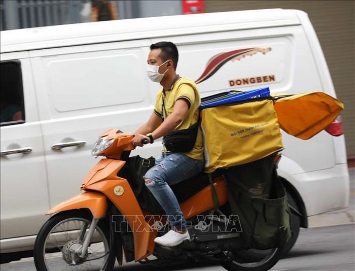 Nhân viên giao hàng không đội mũ bảo hiểm khi di chuyển trên phố (ảnh chụp sáng 10/8/2021).
