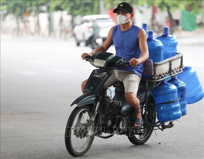 Nhân viên giao hàng không đội mũ bảo hiểm khi di chuyển trên phố (ảnh chụp sáng 10/8/2021).
