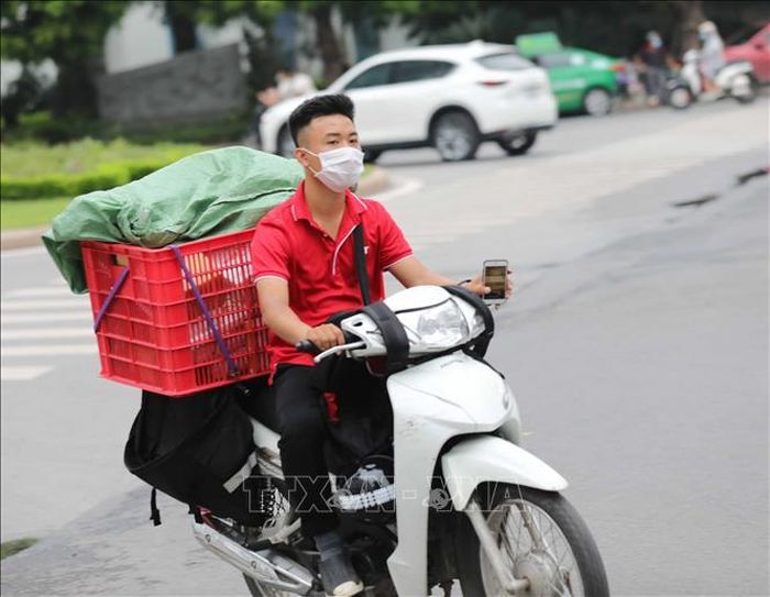 Nhân viên giao hàng không đội mũ bảo hiểm khi di chuyển (ảnh chụp chiều 10/8/2021).