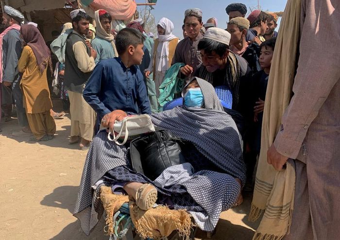  Một người đẩy xe chở một phụ nữ Afghanistan lớn tuổi cùng gia đình nhập cảnh vào cửa khẩu Chaman của Pakistan vào ngày 19/8. Trong khi đó, tại sân bay Kabul, hàng nghìn người Afghanistan đang đứng trước các trạm kiểm soát của Taliban và hàng rào thép gai của quân đội Mỹ xung quanh - nỗ lực tuyệt vọng để tìm chuyến bay rời khỏi đất nước. Ảnh: AP. 