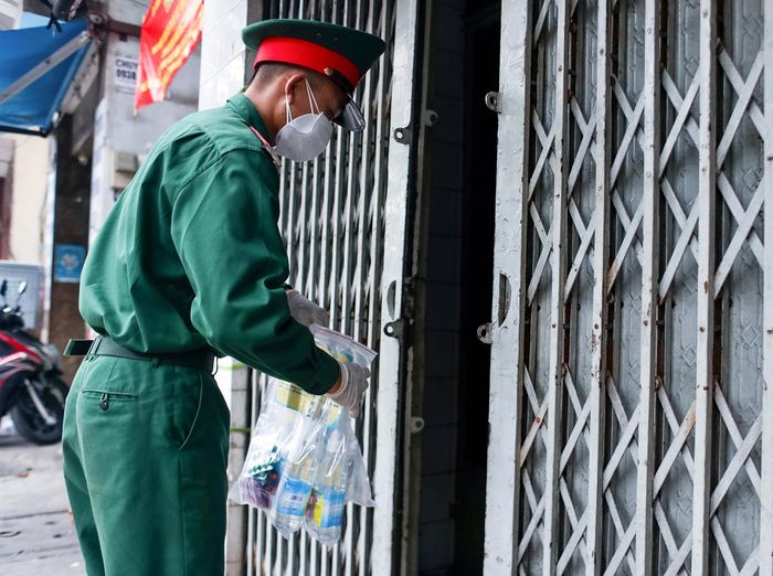  Một chiến sĩ trao thuốc cho một gia đình có 6 ca F0 đang tự điều trị tại nhà trên đường An Dương Vương (quận 5). 