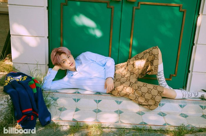 Suga đeo vòng, đi tất, mặc quần áo Gucci và đi giày Saint Laurent.