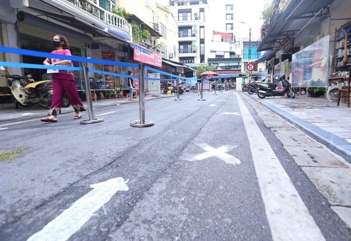 Lực lượng chức năng cho kẻ sơn đánh dấu vị trí nhằm đảm bảo giãn cách. (Ảnh: Hoàng Hiếu/TTXVN)