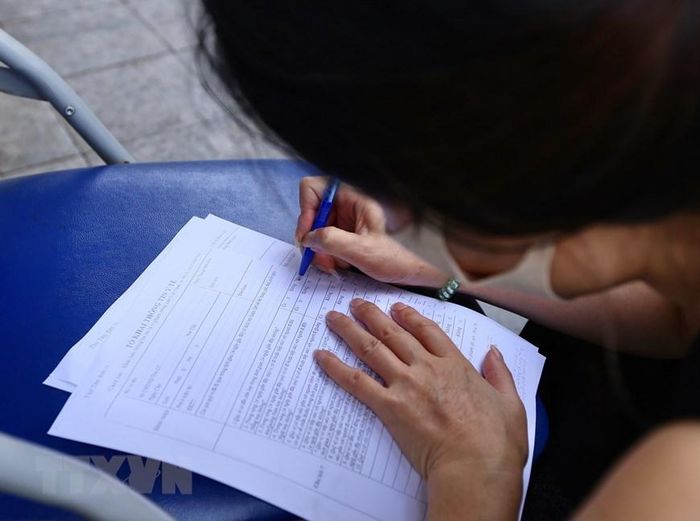 Người dân khai báo y tế trực tiếp khi vào chợ. (Ảnh: Hoàng Hiếu/TTXVN)