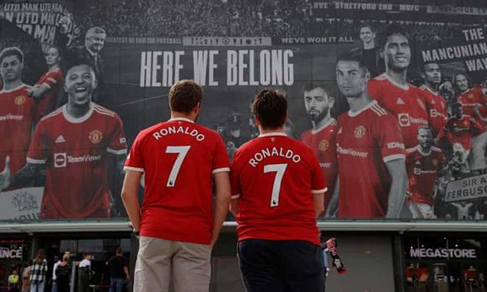 Hai CĐV mặc áo Ronaldo đứng ngắm nhìn poster in hình anh ở Old Trafford