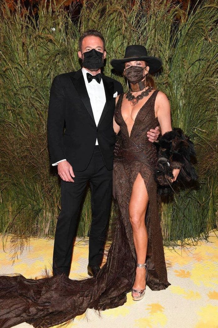 Cặp tình nhân Jennifer Lopez và Ben Affleck tiếp tục là tâm điểm của sự chú ý khi cùng nhau dự sự kiện Met Gala. Trên thảm đỏ, J. Lo diện trang phục cầu kỳ với cổ áo khoét sâu, phần tà xẻ cao cùng chân váy dài, đính lông. Ngôi sao 52 tuổi chọn áo khoác lông thú, mũ lấy cảm hứng từ miền viễn Tây, vòng cổ cùng tông. Trang phục của J. Lo khá rườm rà, thiếu điểm nhấn cụ thể và khiến nữ ca sĩ bị lu mờ hoàn toàn bởi bộ váy. Ảnh: AP.