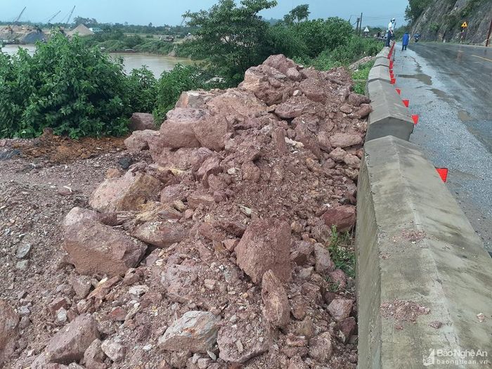 Một số lượng lớn đất đá rơi xuống lòng đường từ hôm qua đã được lực lượng chức năng di chuyển đổ ra phía bờ sông. Ảnh: Huy Thư
