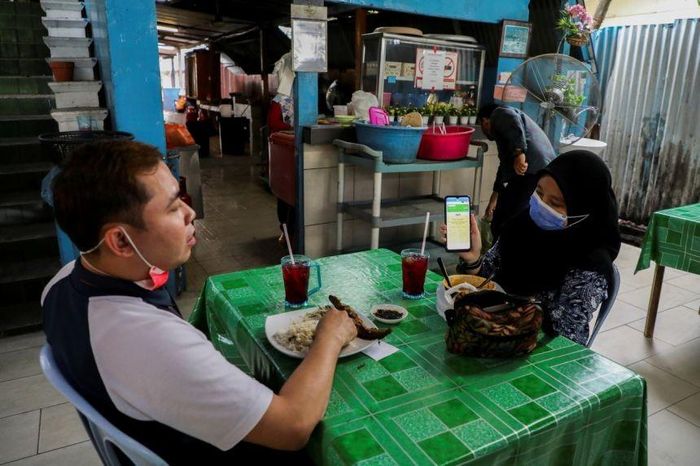 Một người dân trình giấy chứng nhận tiêm vaccine Covid-19 trong nhà hàng tại thủ đô Kuala Lumpur, Malaysia. (Nguồn: Reuters)