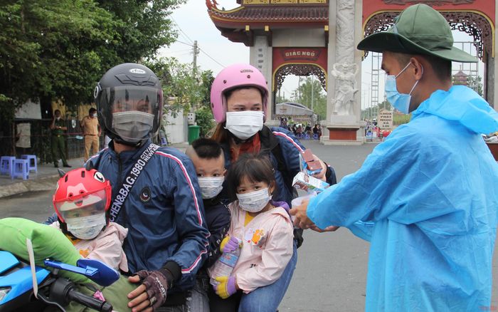 Những gương mặt ngây thơ của trẻ thơ cùng cha mẹ về quê trên chiếc xe gắn máy.
