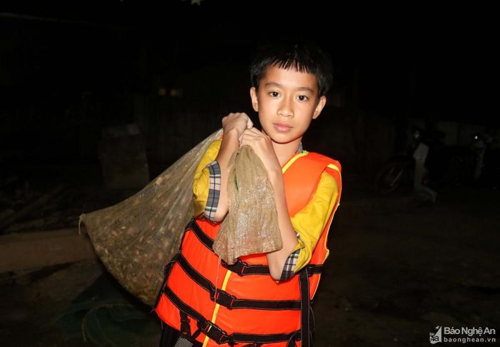 Một em học sinh theo bố đi săn cáy, mang cáy đi bán trong đêm. Ảnh: Huy Thư