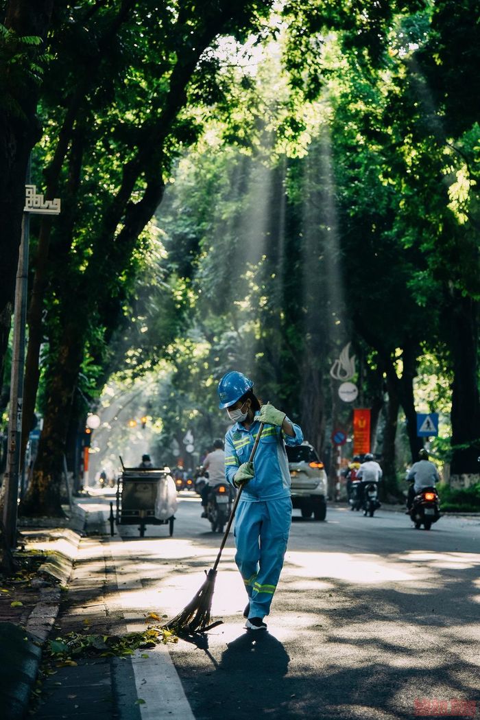 Người công nhân quét dọn lá rụng trên đường do những trận mưa nhiều ngày qua.