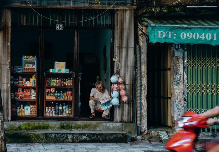 Một người dân ra hiên nhà đọc báo buổi sớm.