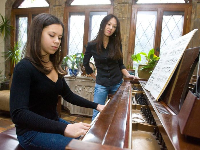  "Mẹ hổ" Amy Chua (bên phải), tác giả cuốn hồi ký "Battle Hymn of the Tiger Mother", yêu cầu hai con Sophie (bên trái) và Lulu luyện đàn 3 tiếng/ngày. Ảnh: Lorenzo Ciniglio/Polaris. 