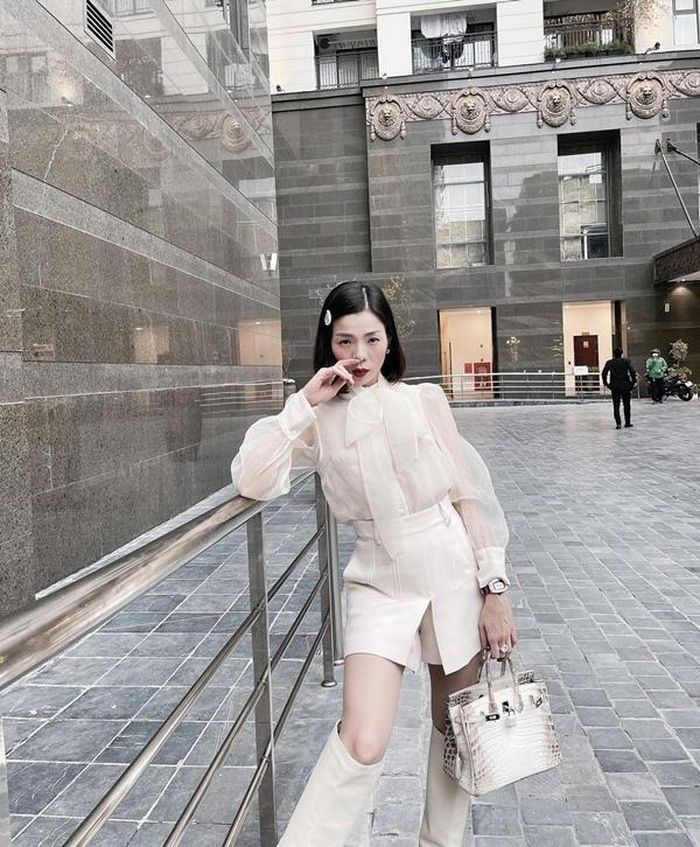 Lệ Quyên như quý cô đài các xuống phố trong set đồ white on white với sơ mi tay bồng cùng boots da thời thượng. Chiếc túi da cá sấu bạch tạng Himalayan Birkin đính kim cương, khóa vàng 18 carat có giá không dưới 3 tỷ đồng được nữ ca sĩ ưu ái dùng nhiều lần đã khiến outfit của cô thật sự đẳng cấp.