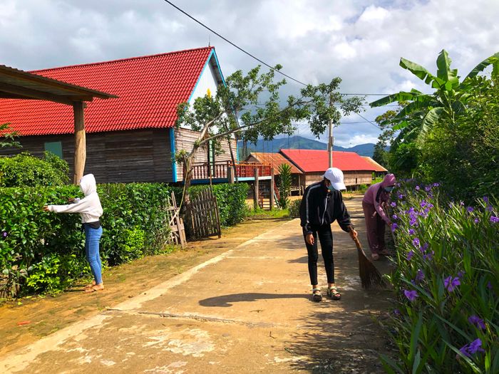 Hội viên phụ nữ làng Nhang Lớn chăm sóc con đường hoa. Ảnh: Ngọc Minh