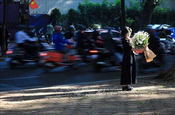 Các bạn trẻ thích thú trải nghiệm và không quên ghi lại những khoảnh khắc nắng sớm mùa thu Hà Nội. Ảnh: Thành Đạt/TTXVN