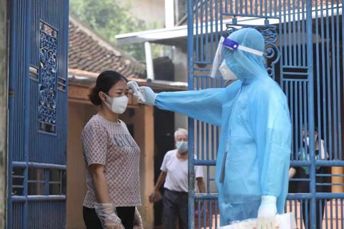 Nhân viên y tế đến kiểm tra thân nhiệt cho người dân trong khu phong tỏa. Ảnh: Minh Quyết - TTXVN