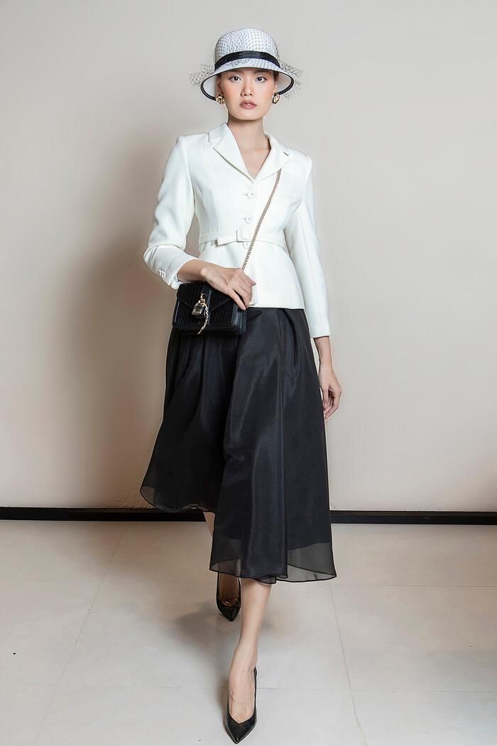 Áo blazer chiết eo dáng ngắn phối cùng chân váy xòe mang đậm phong cách Hàn Quốc là gợi ý hay dịp cuối năm. Lựa chọn hai gam màu cơ bản trắng và đen để làm nổi bật phong cách tối giản sang trọng. Đừng quên phối cùng một chiếc mũ lưới để set đồ thêm kiêu kỳ và phù hợp với những bữa tiệc nhé.