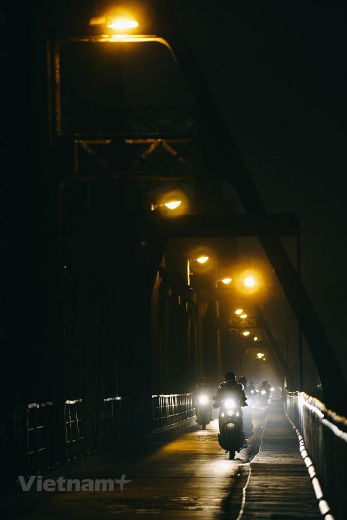  Dòng xe lững lờ 'trôi' trên cầu dưới ánh đèn huyền ảo xuyên qua màn sương mỏng khiến cầu Long Biên buổi tối mùa Đông cũng lãng mạn không kém. (Ảnh: Hoài Nam/Vietnam+) 