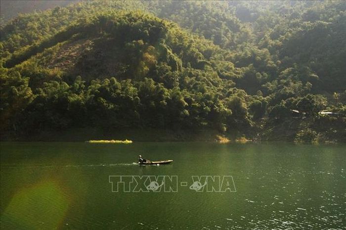 Một người đánh lưới thong thả chèo thuyền trong một buổi sáng bình yên trên hồ Hòa Bình.