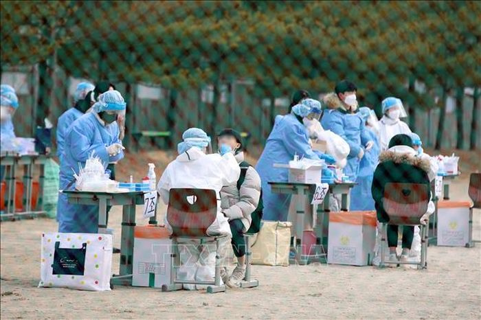 Nhân viên y tế lấy mẫu xét nghiệm COVID-19 cho học sinh tại Gwangju, Hàn Quốc, ngày 28/12/2021. Ảnh: Yonhap/TTXVN