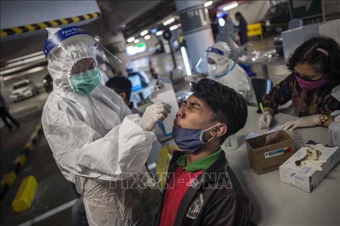 Nhân viên y tế lấy mẫu xét nghiệm COVID-19 cho người dân tại Surabaya, Indonesia. Ảnh: AFP/TTXVN