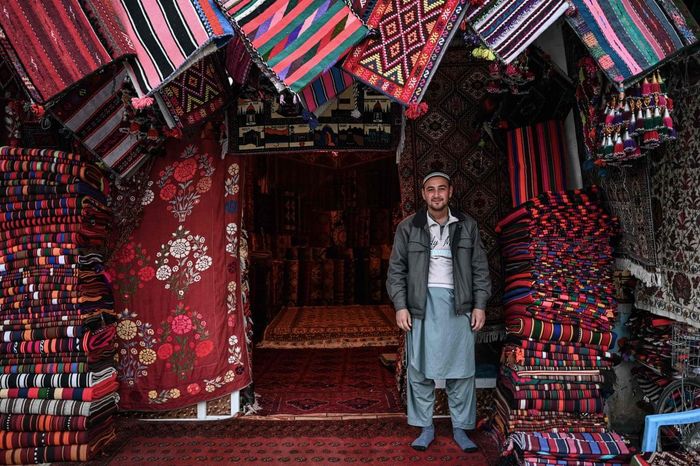 Chủ tiệm bán thảm đứng bên ngoài cửa hàng của mình ở Mazar-i-Sharif. Ảnh: Mohd Rasfan / AFP.