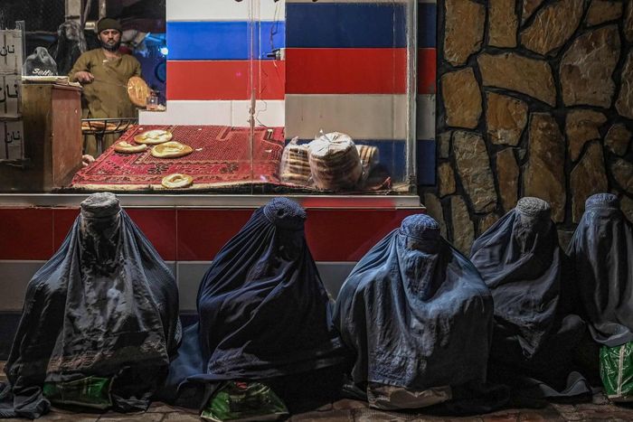 Một số người phụ nữ Afghanistan mặc trên mình chiếc áo choàng burqa, ngồi :ăn xin" trước tiệm bánh ở Kabul. Ảnh: Mohd Rasfan / AFP.