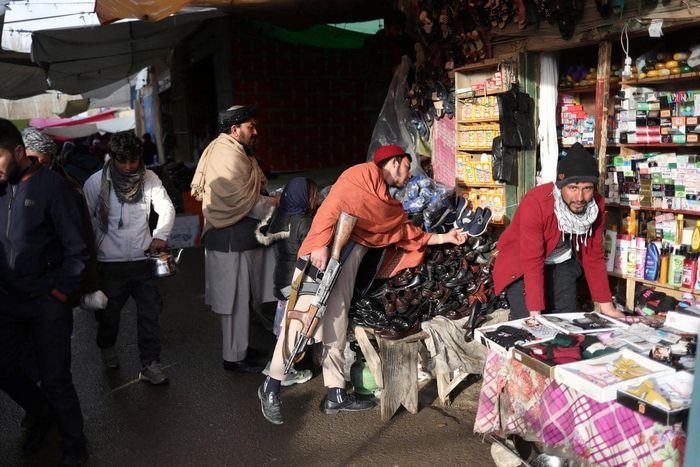 Một thành viên của lực lượng an ninh Taliban kiểm tra giày dép tại một khu chợ ở Bamiyan. Ảnh: Ali Khara / Reuters.