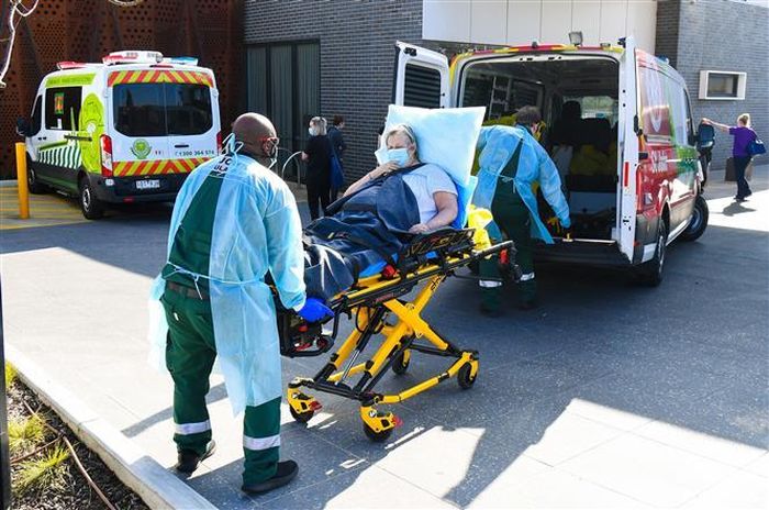 Nhân viên y tế chuyển bệnh nhân COVID-19 tới bệnh viện tại Melbourne, Australia. Ảnh: AFP/ TTXVN