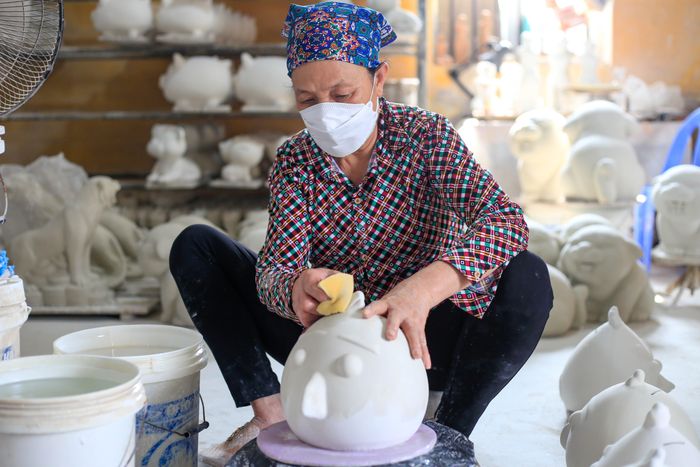  Người thợ phải dùng mút đánh bóng sản phẩm trước khi đến bước phun sơn và trang trí. Những đợt cận Tết hoặc sát ngày giao hàng, xưởng phải đẩy nhanh quá trình làm để kịp giao cho khách. 