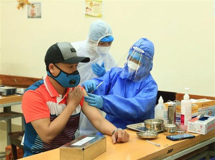Người dân được tiêm vaccine AstraZeneca tại điểm tiêm Trường THCS Trưng Vương, sáng 7/1/2021. Ảnh: Hoàng Hiếu - TTXVN