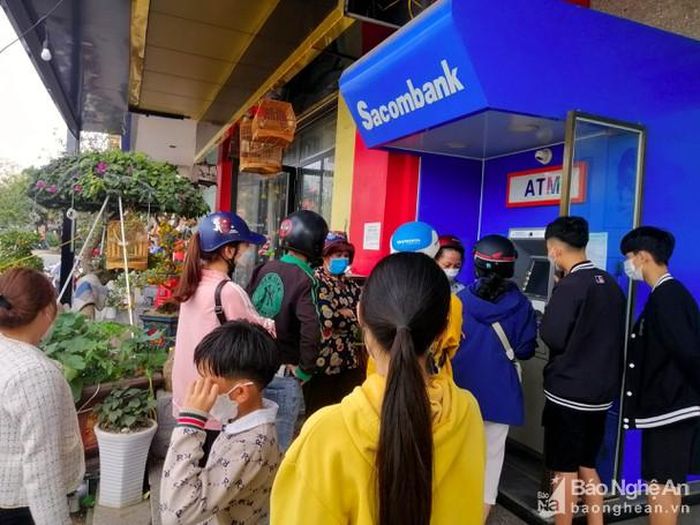 Mỗi cây ATM đều có cả chục người vây quanh để mong đến lượt mình rút tiền. Chị Nguyễn Hồng Hạnh, xã Diễn Phúc chia sẻ: "Do biết năm nào cũng đông đúc người rút tiền dịp Tết nên từ sáng sớm, tôi đã phải tranh thủ lúc vắng người để rút tiền, nào ngờ đến nơi vẫn phải xếp hàng vì đã có người đến rút trước...". Ảnh: Quang An