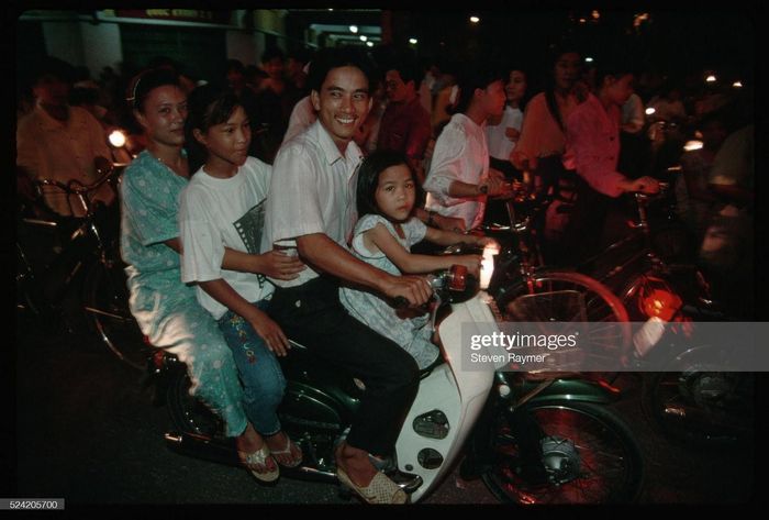 Một gia đình bốn người vi vu trên xe Honda Cub vào buổi tối.