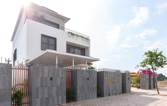 Mặt tiền phía ngoài được nhấn bởi khối hàng rào ốp đá mạnh mẽ xen lẫn hệ lam gỗ nhựa