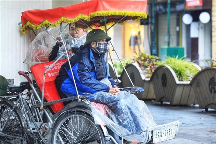 Một người đạp xích lô du lịch chờ khách co ro trong giá rét trên phố Đinh Tiên Hoàng.
