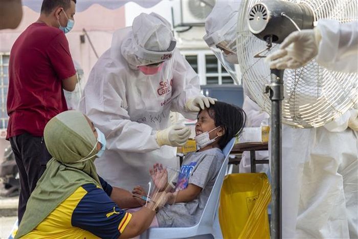 Nhân viên y tế lấy mẫu xét nghiệm COVID-19 cho trẻ em tại Selangor, Malaysia. Ảnh: THX/ TTXVN